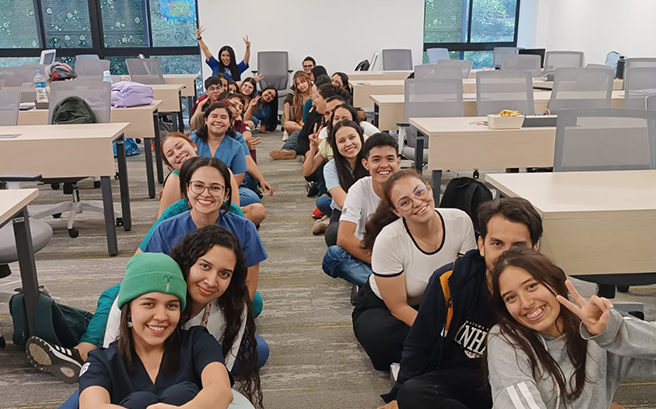 Estudiantes sentados en linea recta sonriendo.